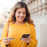 Joyful girl with headphones in her ears shopping online